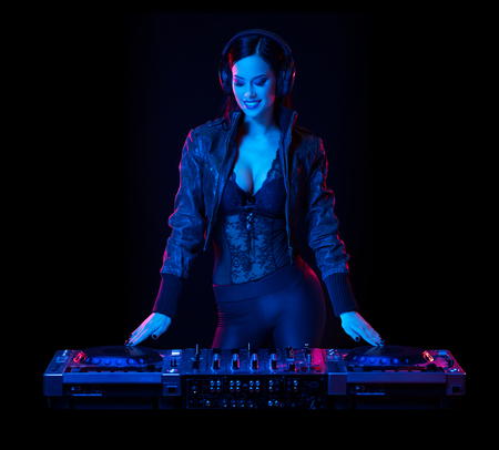 Gorgeous young female DJ in colorful stage lighting.の写真素材