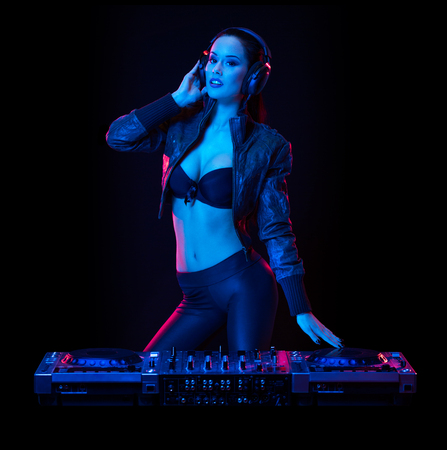 Gorgeous young female DJ in colorful stage lighting.の写真素材