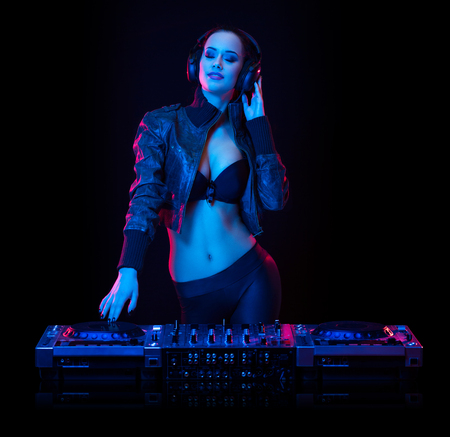 Gorgeous young female DJ in colorful stage lighting.の写真素材