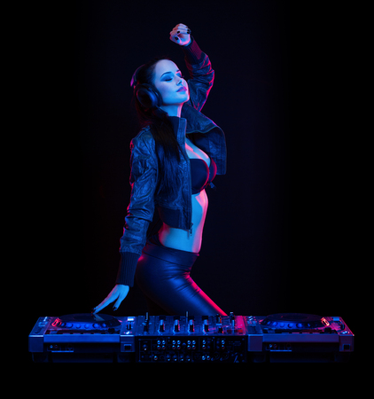 Gorgeous young female DJ in colorful stage lighting.の写真素材