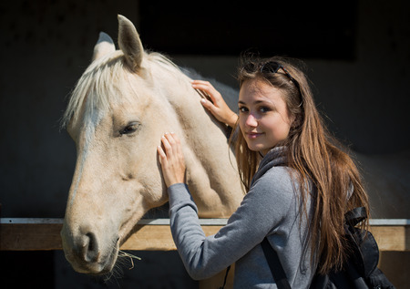 Beautiful young brunette woman befriending champagne color horse.の写真素材