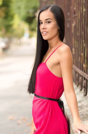 Portrait of a brunette beauty outdoors in pink summer dress.の写真素材