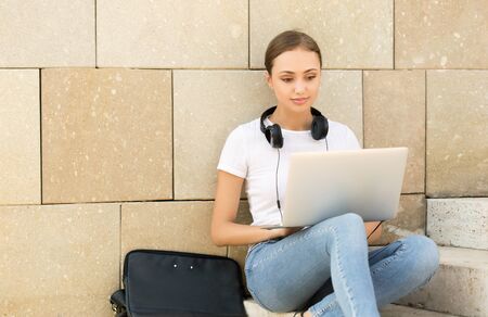 Portrait of attractive young brunette student using her laptop outdoors.の写真素材