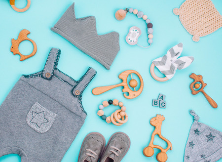 Baby accessories concept. Baby clothes and wooden toys on light blue background. Top view, flat lay.の写真素材