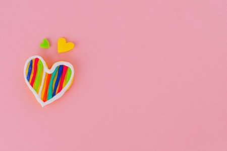 Handmade plasticine hearts on pink background with copy space