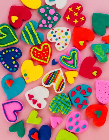 Colorful handmade plasticine hearts on pink backgroundの写真素材