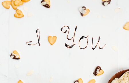 Letters "I LOVE YOU" made with chocolate and heart shape cookie on light background. Top view, flat lay. の写真素材