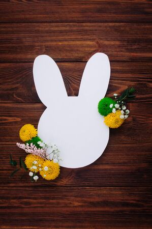 Happy Easter greeting card. Easter bunny from white paper with flowers on rustic wooden background with blank space for text. Top view, flat lay.の写真素材