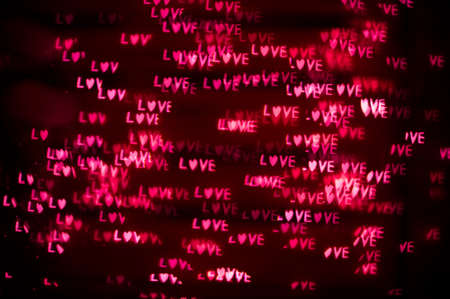 Abstract romantic background of defocused bokeh with word love, on black backgroundの写真素材