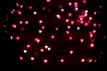 Abstract romantic background of defocused heart-shape bokeh, on black backgroundの写真素材