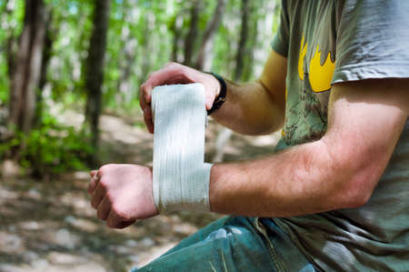 Applying an arm medical bandage in a forest during the journeyの写真素材