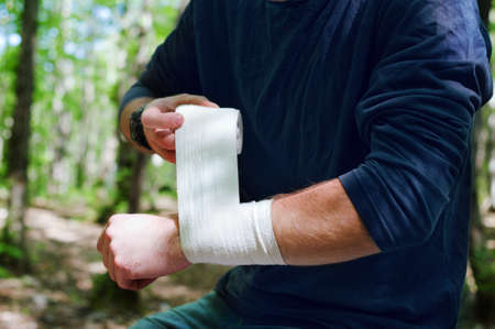 Applying an arm medical bandage in a forest during the journeyの写真素材
