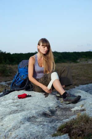 Portrait of a female tourist applying an arm medical bandage in mountains during the journeyの写真素材
