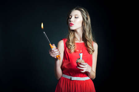 Young woman holding birthday cupcake and lighterの写真素材