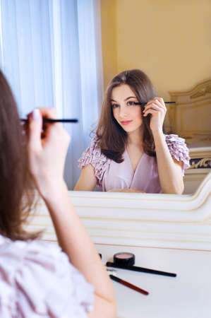 Portrait of beautiful young woman putting on makeup holding a brushの写真素材