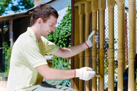Young man painting wooden fence in the gardenの写真素材