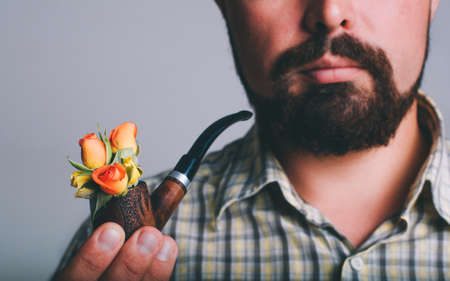 Portrait of man with beard and smoke pipe with rose flowers inside itの写真素材