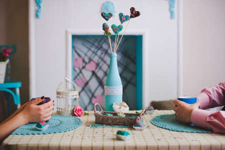 Love concept shot with unrecognizable couple sitting opposite each other. Hands holding cups of...