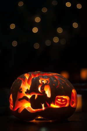 Halloween pumpkin with light inside over black background with bokehの写真素材