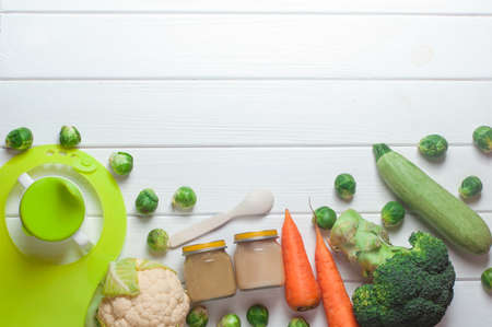 Glass jars with natural baby food vegetable puree with Brussels sprouts, squash, broccoli, cauliflower, on the white wood tableの写真素材