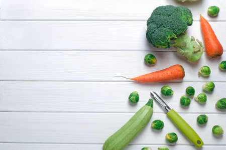 Brussels sprouts, carrot, squash, broccoli and peeler on the white wood backgroundの写真素材