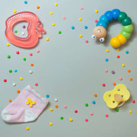 Baby accessories concept: sock, teether, caterpillar toy and baby pacifier, over gray background with copy space; top view, flat lay.の写真素材