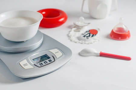 Rice porridge ready for baby first lure on kitchen scale on white table