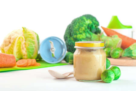 Glass jar with natural baby food on the table, isolated on white background: vegetable puree with Brussels sprouts, squash, broccoli, cauliflower; selective focusの写真素材