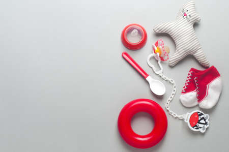 Baby accessories background: socks, soother, nipple, spoon and toys over gray background with copy space; top view, flat lay.の写真素材