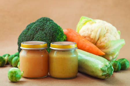Glass jar with natural baby food on the table: vegetable puree with Brussels sprouts, carrot, squash, broccoli, cauliflower; selective focusの写真素材