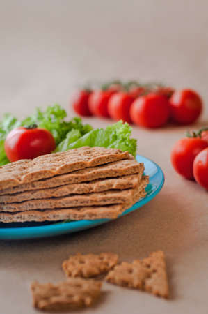 Healthy food concept: Close up of crispbreads near cherry tomato on the light brown background. Selective focus.の写真素材