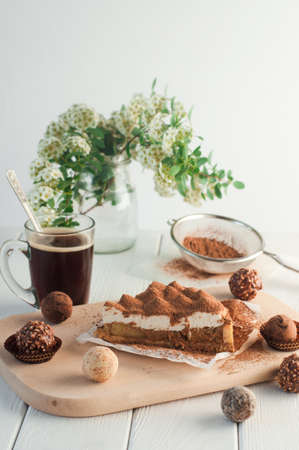 A piece of apple pie with whipped cream covered by grated chocolate near chocolate truffle candies. Selective focus and small depth of field.の写真素材