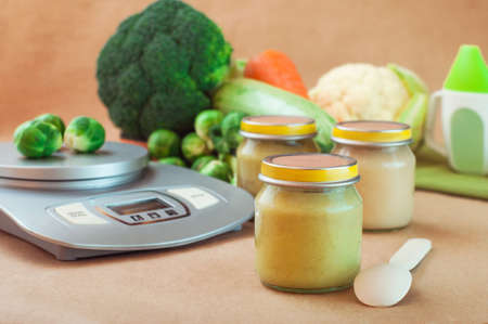 Glass jar with baby food near kitchen scalesの写真素材