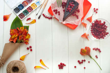 Flowers, paints and cake on the white wooden backgroundの写真素材