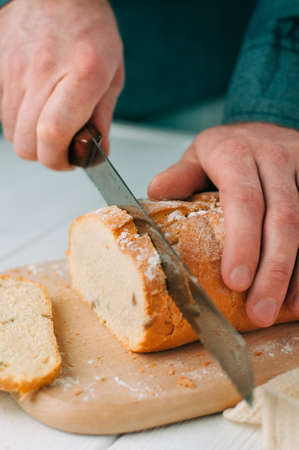 Male hands cutting wheaten breadの写真素材