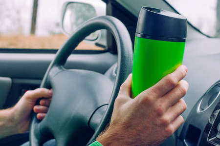 Males hand holding thermo mug with coffeeの写真素材