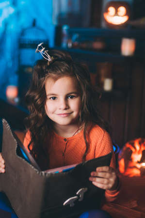 Little girl in a costume of witch with magic bookの写真素材