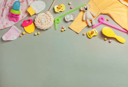 Baby accessories background: socks, soother, brush, clothes and toys over gray background with copy space top view, flat layの写真素材