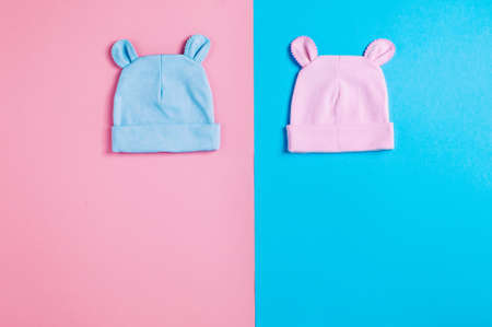 Baby accessories background: funny baby's caps with ears over pink and blue background with copy space top view, flat layの写真素材
