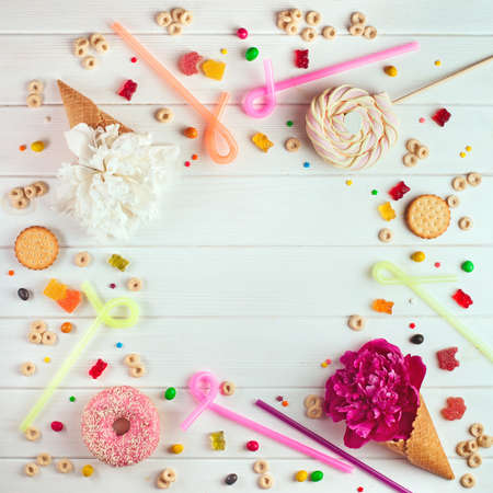Birthday party background design concept: candies, flower ice cream, donut and biscuits on the white wooden background with copy space top view, flat layの写真素材