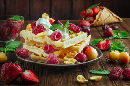 Belgian waffles with raspberry, strawberry, whipped cream and grated chocolate on white wooden background selective focusの写真素材