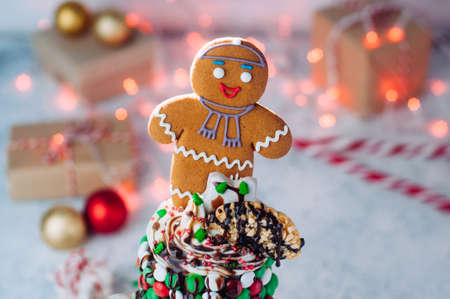 Close up of Christmas freak shake topping with gingerbread man, whipped cream and melted chocolate...