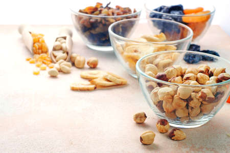 Close up of dried fruits, nuts and seeds in glass bowls on light beige background with copy space selective focusの写真素材