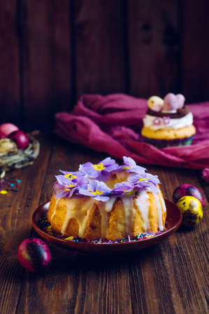 Happy Easter card: traditional Easter ring cake decorated with flowers and painted quail eggs on rustic wooden background selective focusの写真素材