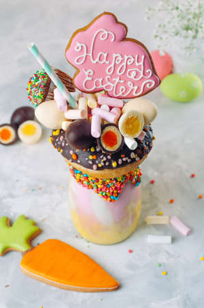 Easter freak shake decorated with Easter bunny gingerbread topping with donut, chocolate eggs and...