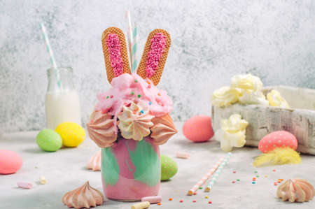 Easter freak shake decorated with rabbit ears cookies topping with meringue and cotton candy on party table selective focusの写真素材