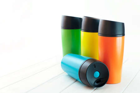 Color thermal mugs on the white wooden table on white background with copy space selective focus