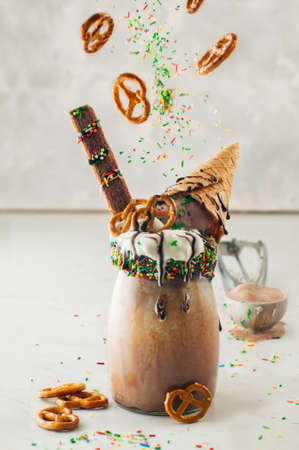 Freakshake topping with whipped cream and ice cream waffle cone on light background selective focus....