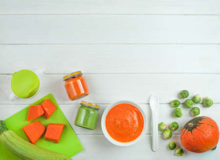 Natural baby food on the white wooden background: home made vegetable puree with pumpkin, squash and Brussels sprouts top view, copy space.の写真素材