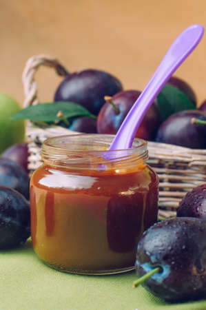 Natural baby food concept: jar with prune puree on the table near fresh plums selective focusの写真素材